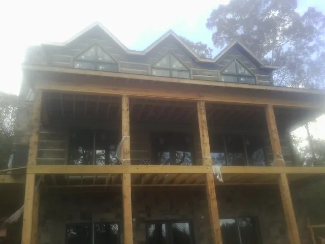 Dormers and porch framing on a large log home under construction — Roof Coating work by our crew in Clinton